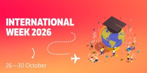 Promotional poster for International Week 2026, taking place 26–30 October. The background has an orange‑to‑pink gradient. On the right side, an illustrated globe wearing a graduation cap symbolizes global education. Around the globe, small groups of people are shown reading, talking, and interacting, with speech bubbles containing different national flags to represent international communication. A dotted travel line with a small airplane icon suggests global connection and mobility. The event title “International Week 2026” and the dates “26–30 October” appear on the left.